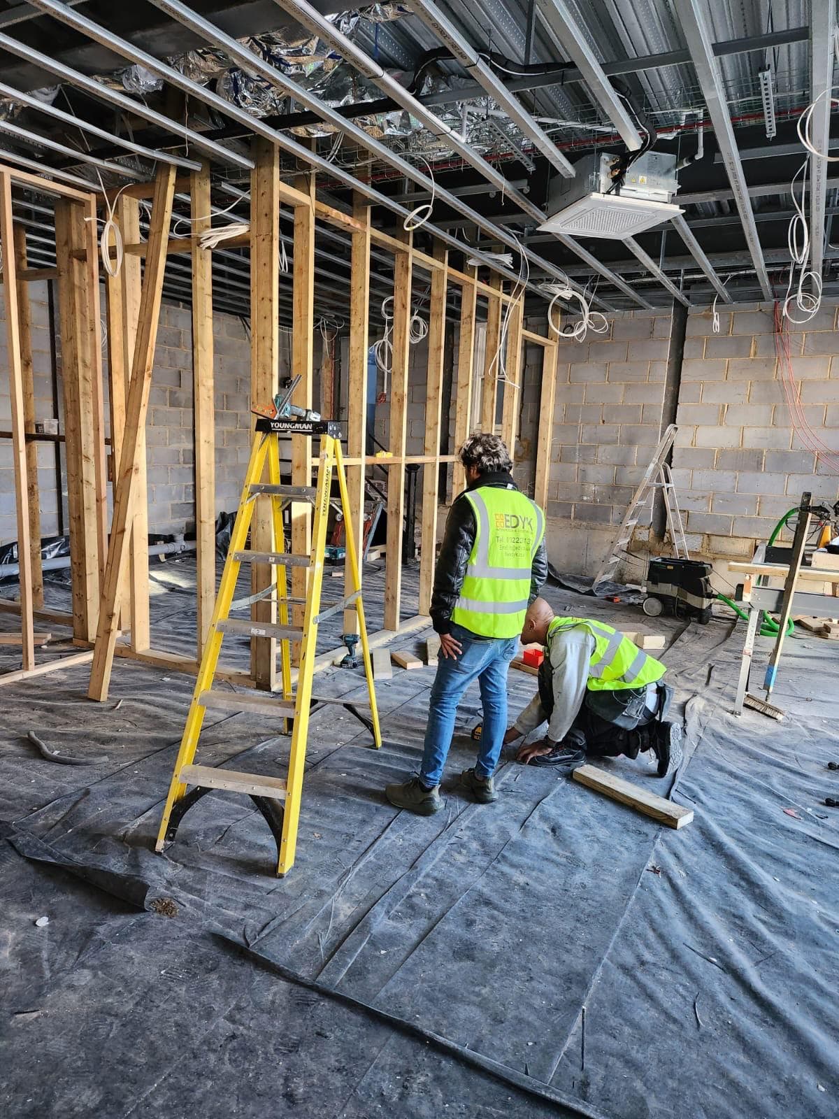 EDYK team framing timber stud walls in the bare shell of the Lebanese House unit